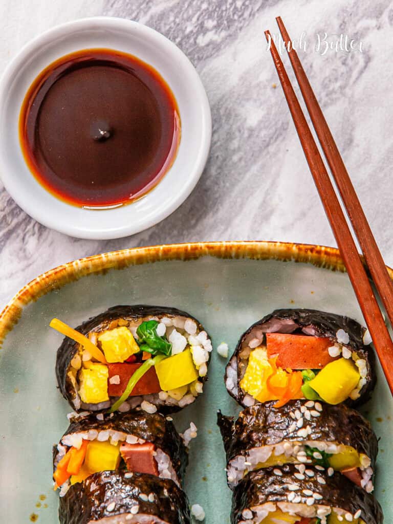 Spam Kimbap is really what you need! A delicious Korean-style sushi roll filled with warm rice, spam meat, spinach, yellow pickled radish, egg, and carrots.